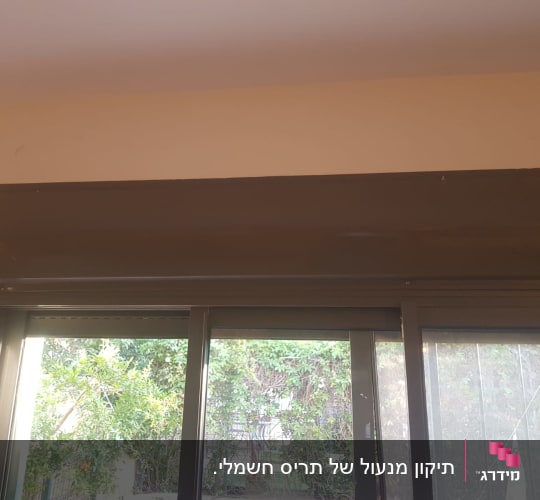 תריסים סגורים עם קופסת תריס חומה מעל החלון